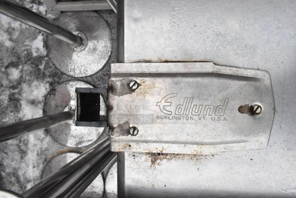 Commercial table with Edlund can opener mount, stainless steel construction, visible wear, includes under shelf.