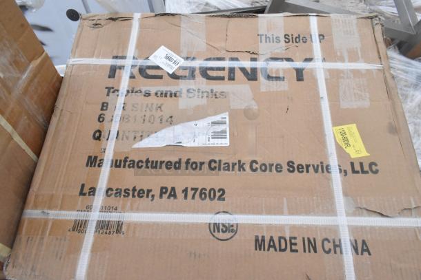 Cardboard box labeled Regency, containing new scratch and dent items like anti-fatigue mat and sink from Clark Core Services.