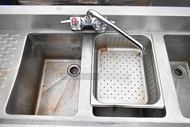 Commercial 4 bay back bar sink with dual drain boards, faucets, and handles. Stainless steel, showing moderate wear.