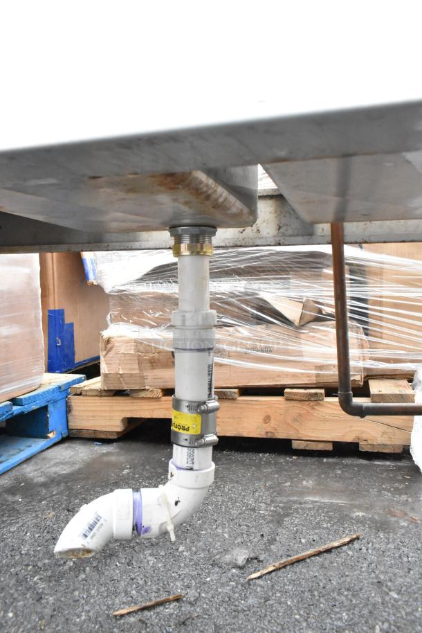 Commercial 4-bay back bar sink with dual drain boards, visible underside plumbing, faucets, and condition marks.