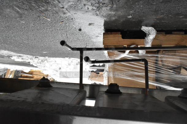 Commercial 4-bay back bar sink with dual drain boards, faucets, and handles. Appears used, outdoor setting.