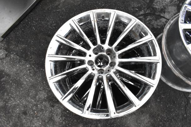 "AMG chrome finish rim with multi-spoke design, slight wear visible, AMG branding. Auction includes four rims."