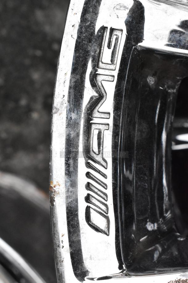 AMG chrome finish rim, featuring "AMG" logo, slight wear visible. High-quality automotive part, ideal for luxury vehicles.