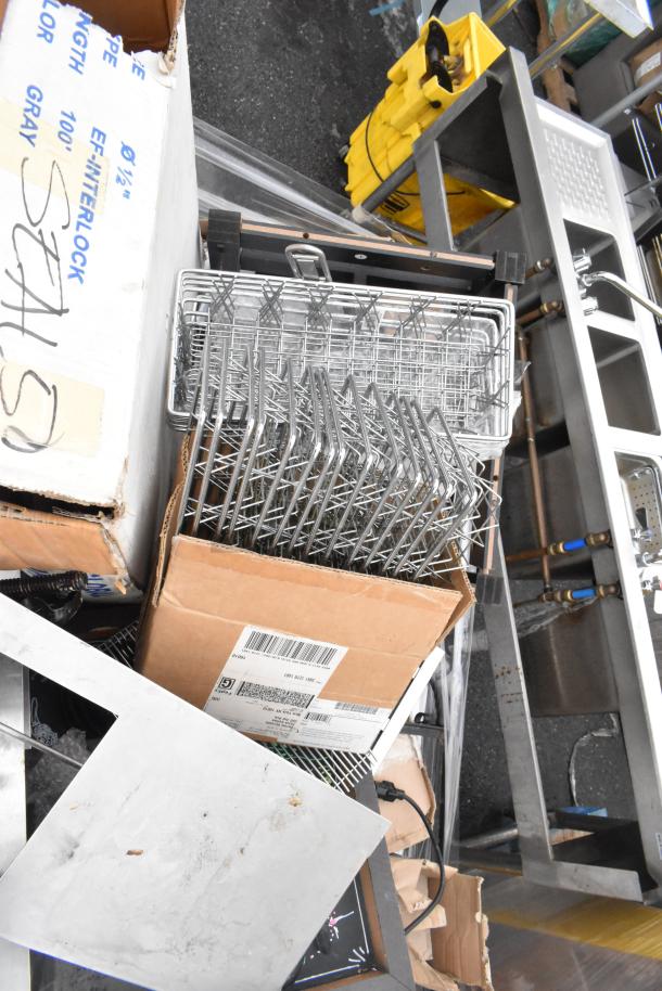 Pallet of various items including metal baskets, boxes, and a hose. Light fixture part visible. Items in mixed condition.