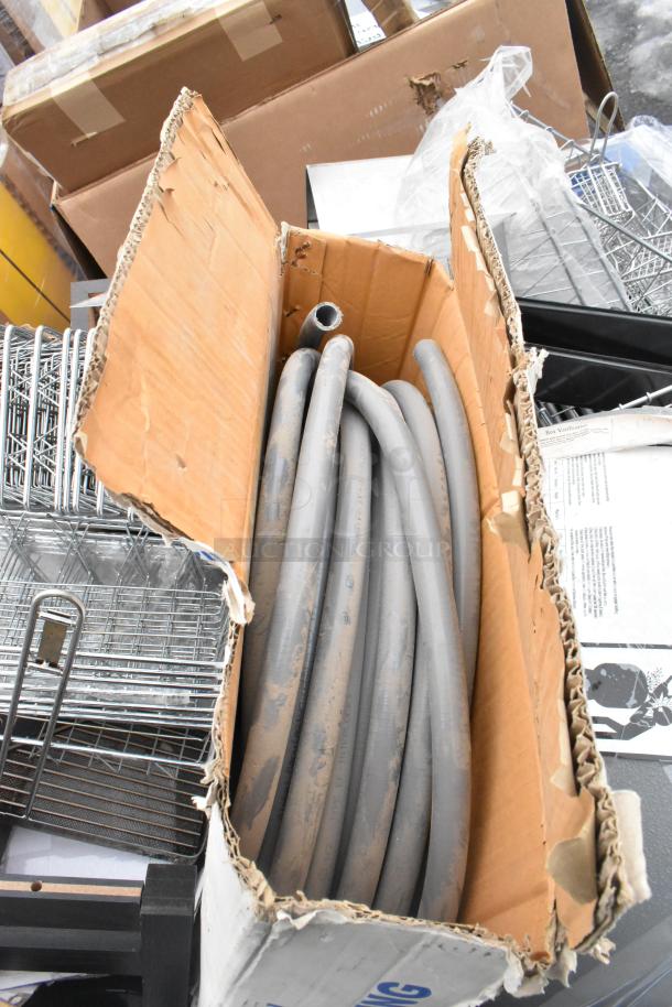 Pallet lot featuring metal baskets, light fixture, and a coiled hose in a cardboard box. Mixed condition.