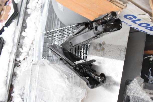 Pallet of miscellaneous items, including metal baskets, light fixture, and hose, with visible metal jacks and cardboard boxes.