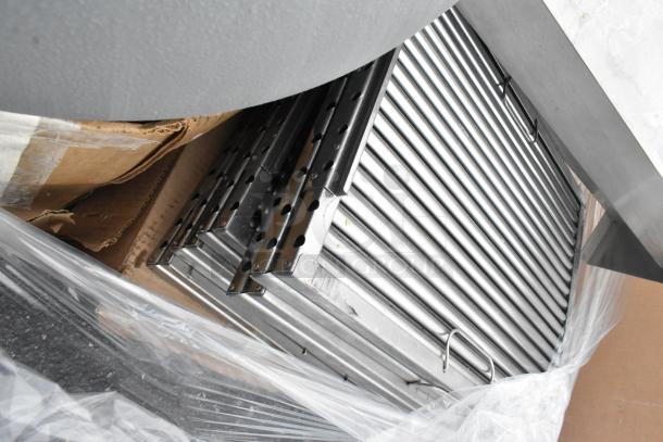 Pallet lot with metal baskets, a light fixture, and hose. Items stored on a pallet, condition appears good with visible packaging.