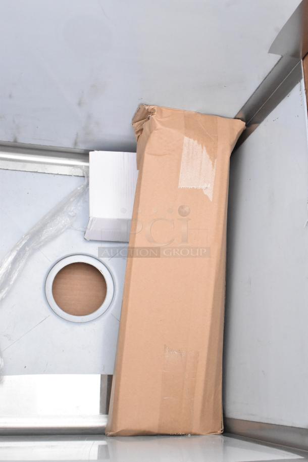 Cardboard box containing brand-new items, including Koala Kare Infant Seat Kradles, utility sink, and ice bin, in scratch and dent condition.