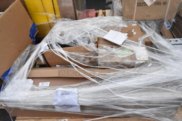 Stack of packaged new scratch and dent items, including Avantco over shelf and Watts grease trap, wrapped in plastic.