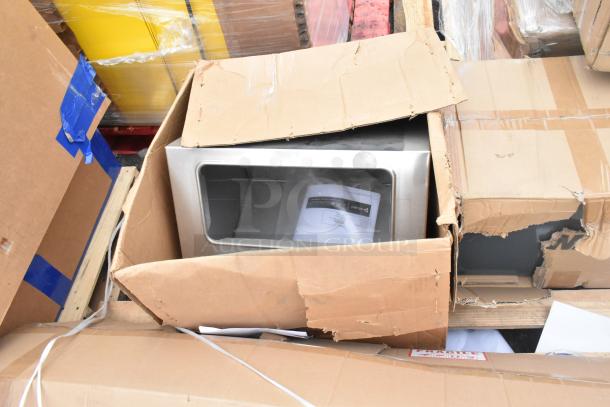 Cardboard boxes containing brand new scratch and dent items, including a metal unit with a label, part of a 7-item auction lot.