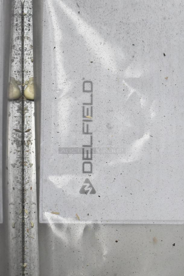 Close-up of a Delfield logo on packaging, indicating potential inclusion in the auction lot of new items with minor defects.
