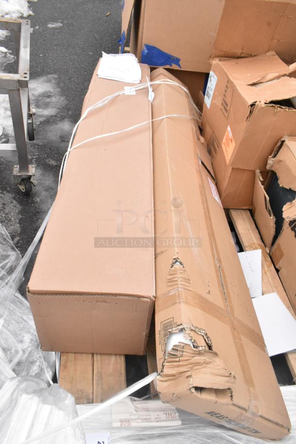 Stack of cardboard boxes containing 7 brand new scratch and dent items, including Avantco Over Shelf and Watts Grease Trap.