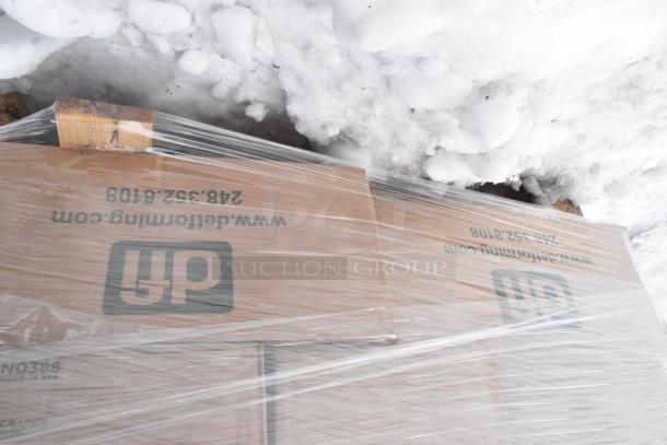Pallet with boxed items wrapped in plastic. Boxes show "UP" and "detroitforming.com" markings, set on snow.