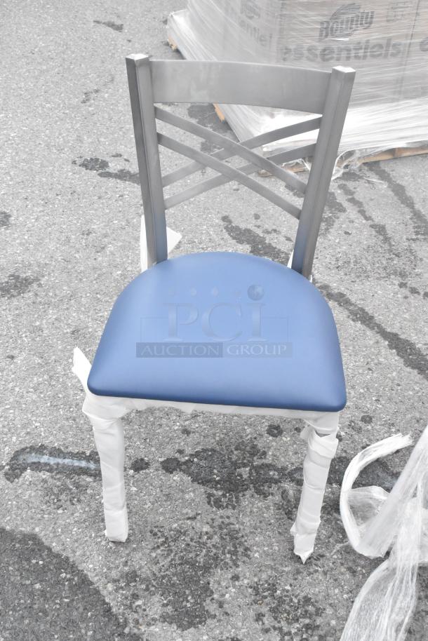 Metal-frame chair with blue cushioned seat, partially wrapped in protective packaging, labeled "Scratch and Dent."
