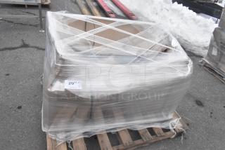 Brand new Regency 600S21824 sink, scratch and dent, wrapped in plastic on a pallet, with auction tag visible.