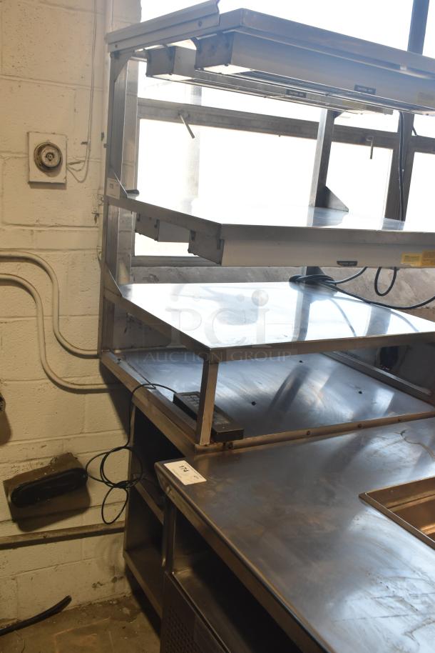 Commercial multi-shelf merchandiser display with warming strips, stainless steel, industrial use, moderate wear visible.