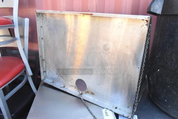 Metal shelf with visible rust and chain, rectangular shape, hole in center. Used condition with some wear.