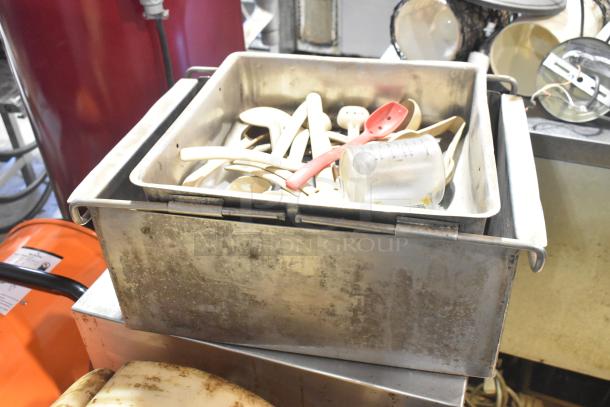 Commercial floor style unit with stainless steel body, containing utensils and a glass measuring cup. Mild wear visible on the surface.