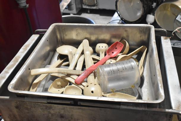 Commercial floor style unit featuring a metal container filled with various kitchen utensils, including spoons and a measuring cup.