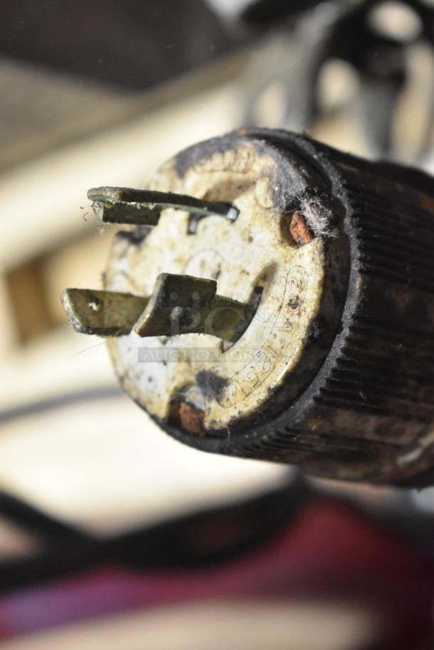 Close-up of a worn electrical plug with visible rust and debris, part of a commercial floor style unit.