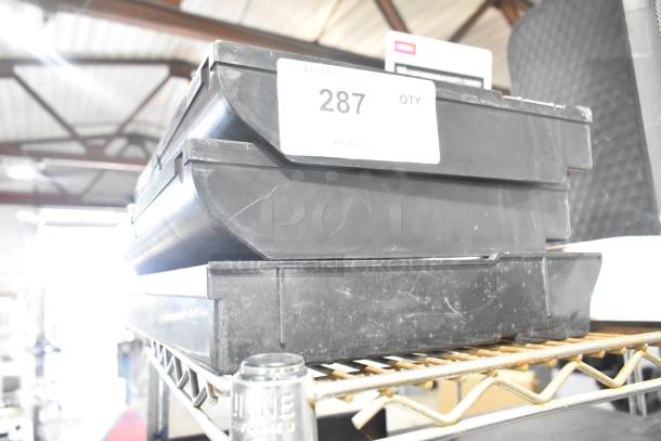 Lot of 3 black poly cash register inserts, lightly worn, stacked on a shelf with label "287 QTY" visible.