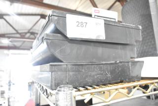 Lot of 3 black poly cash register inserts, lightly worn, stacked on a shelf with label "287 QTY" visible.