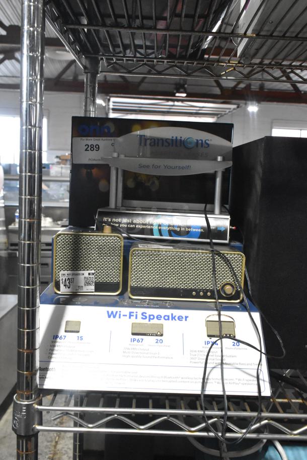 Two Onn Wi-Fi speakers with brass accents, IP67 rating, 20W RMS output, on display shelf. Price tag showing $43.37.