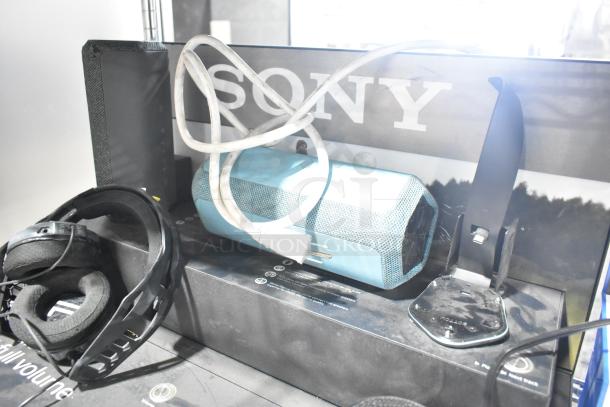 Sony display with speakers and headphones, accompanied by blue Onn speakers. Items showcase good condition.