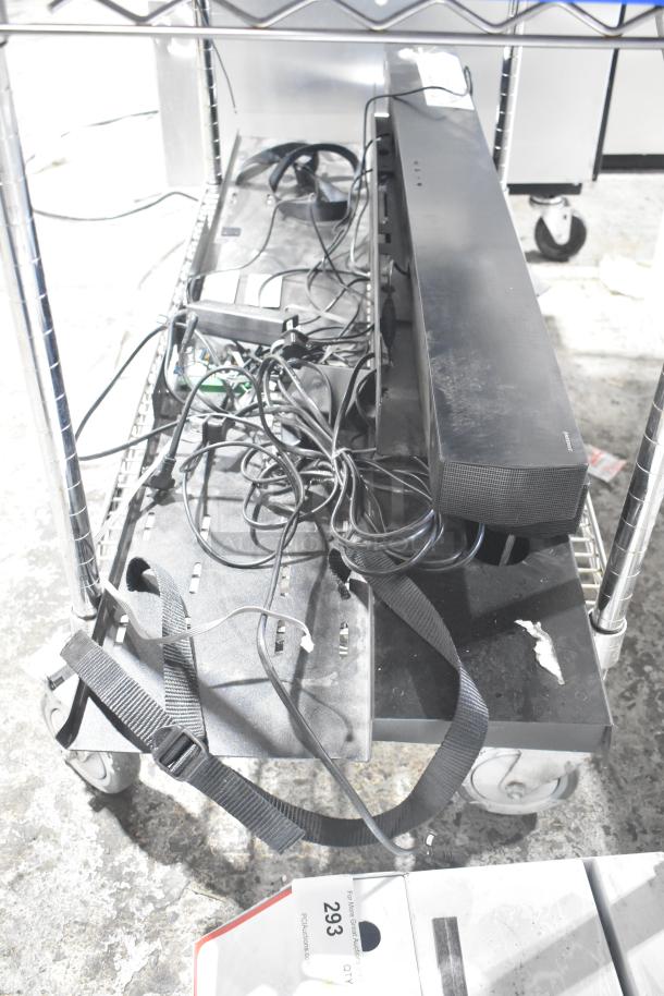 Metal display rack with two shelves, attached wheels, and scattered cables. Visible sticker reads "293" indicating item ID.