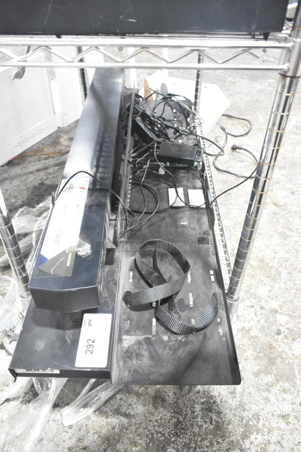 Metal display rack with multiple shelves, wires, and a strap. Tag reads "292 QTY." Condition appears used.