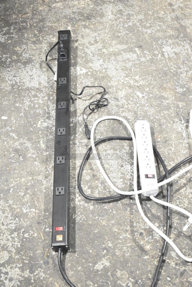 Two power strips; one black, one white. Black strip has eight outlets, white strip has six outlets with a reset switch.