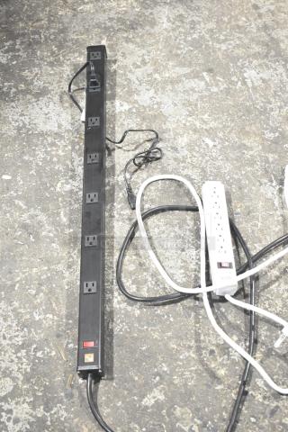 Two power strips; one black, one white. Black strip has eight outlets, white strip has six outlets with a reset switch.