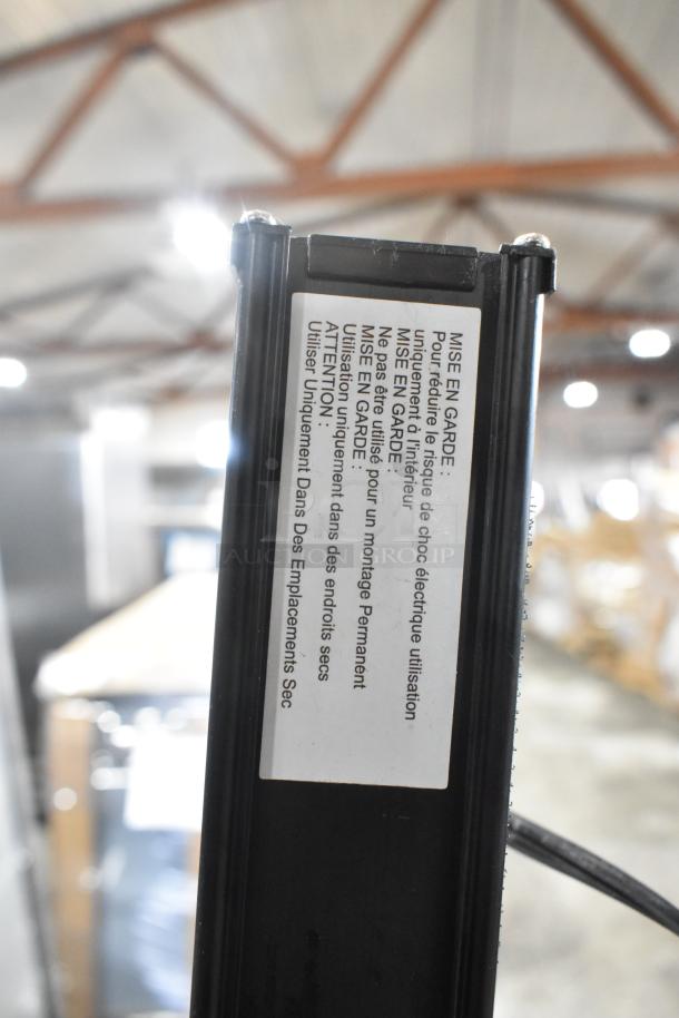 Two power strips, black with caution label for indoor use only, shown in a warehouse. Condition appears good.