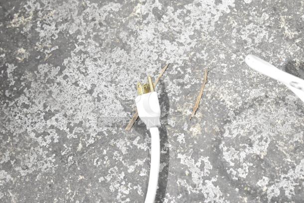 Close-up of a white power strip plug on a textured surface, showing three-prong design.