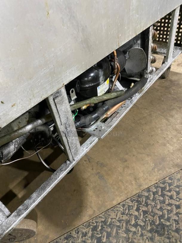 True TUC-48 commercial stainless steel 2-door worktop refrigerator, visible interior mechanics, poly-coated wired rack, on casters.