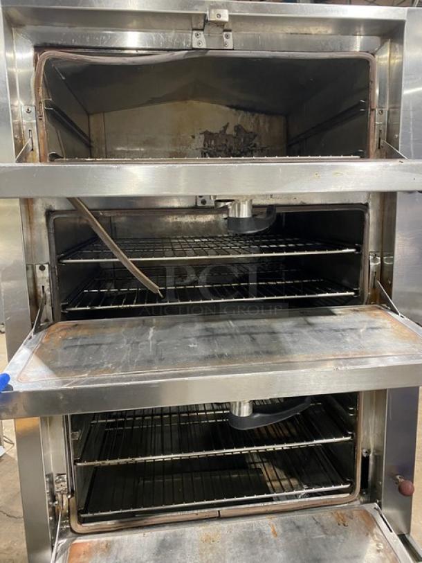 Commercial stainless steel 3-compartment seafood steamer, gas-powered, with individual controls and wired oven rack, on legs.