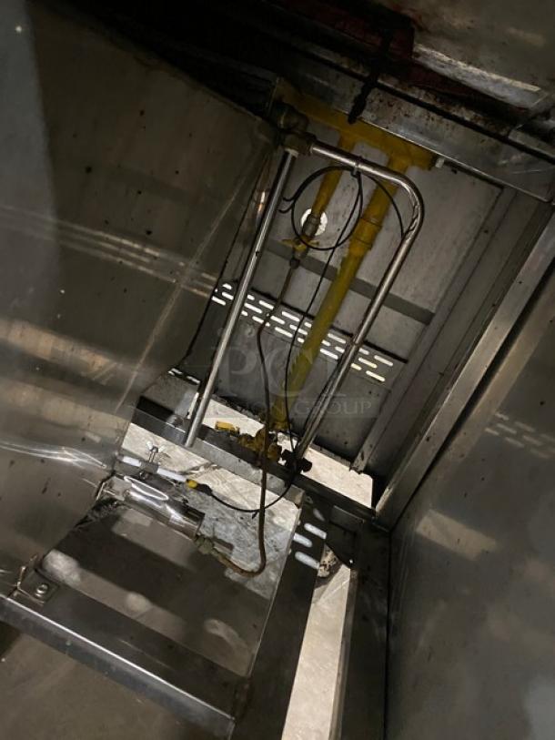 Commercial stainless steel three-compartment seafood steamer with individual controls and wired oven rack, in used condition, on legs.