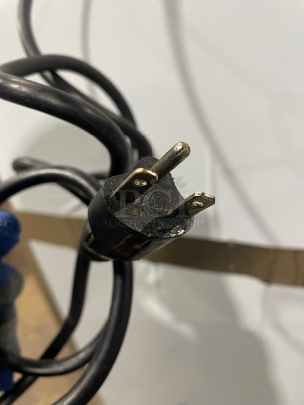 Close-up of a black electric plug of the Alto-Shaam 1200-UP/SR. The plug appears intact, with two prongs and a rounded end.