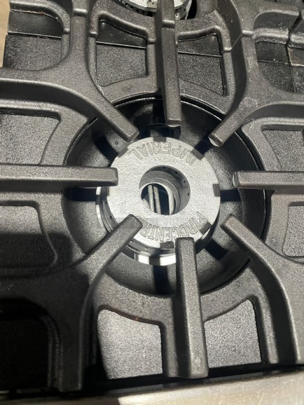 Imperial commercial stainless steel 6-burner range with branded burner detail. Features overhead salamander shelf, backsplash, and wired oven rack.