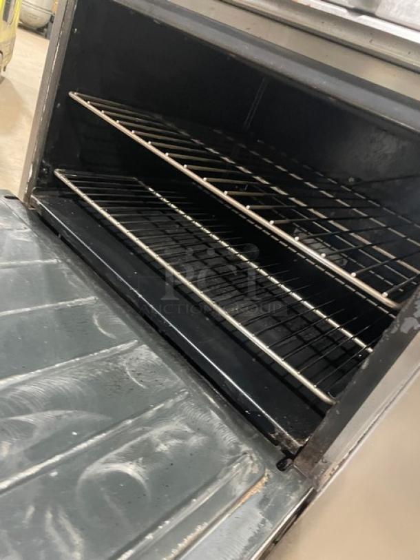 Imperial Commercial 6-burner range/oven combo with overhead salamander shelf, backsplash, and wired oven rack. Stainless steel.