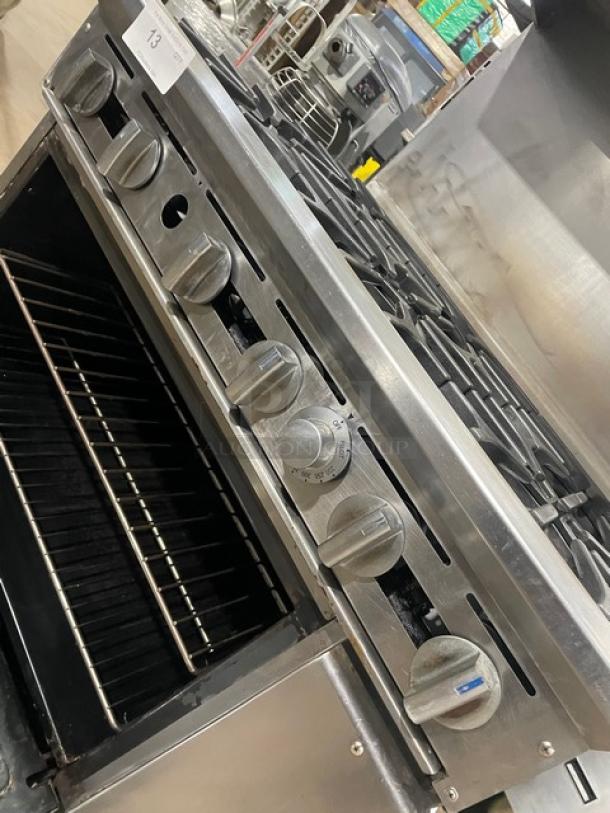 Imperial commercial stainless steel 6-burner range/oven combo with overhead salamander shelf, wired oven rack, and backsplash.