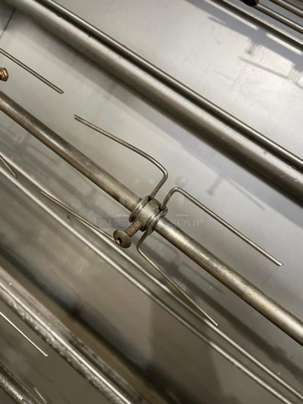 Attias stainless steel gas-powered full-height rotisserie cabinet on casters, featuring sturdy metal skewers and robust construction.