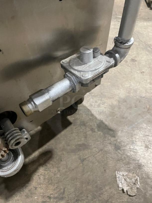 Attias stainless steel gas-powered rotisserie cabinet on casters, showing gas connection detail. Clean condition.