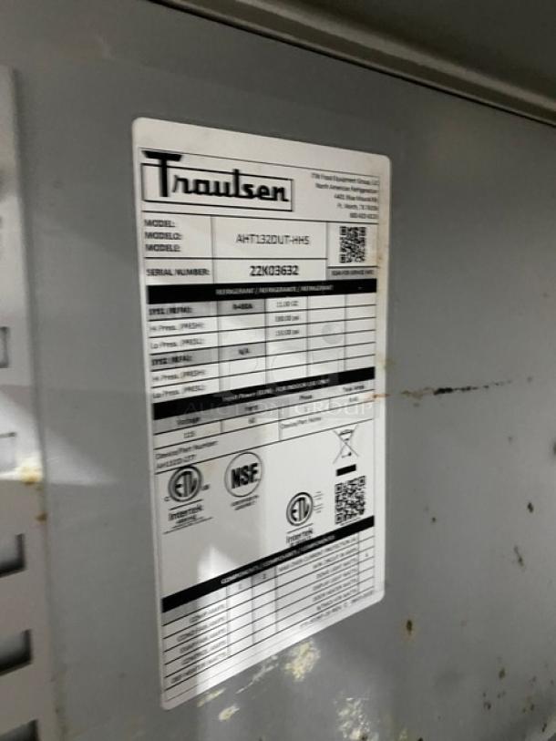 Traulsen commercial refrigerator model AHT132DUTHHS with label showing specs; stainless steel, half-door, on casters.