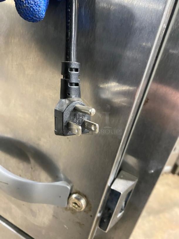 Traulsen stainless steel reach-in refrigerator, Model AHT132DUT-HHS, with wired racks, on casters, visible power plug.