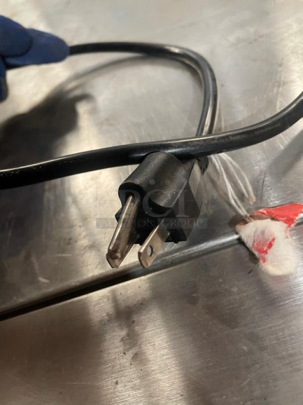 HeyCafe HC600 espresso grinder power cord, black, with standard 110V plug, seen on a stainless steel surface.