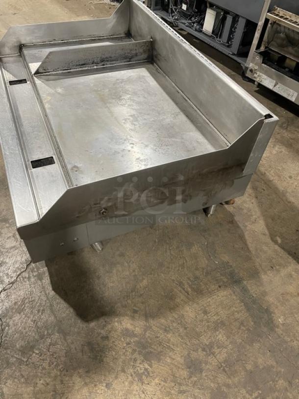 WoodStone stainless steel gas-powered plancha griddle with split-top, back and side splash, on legs, commercial use.