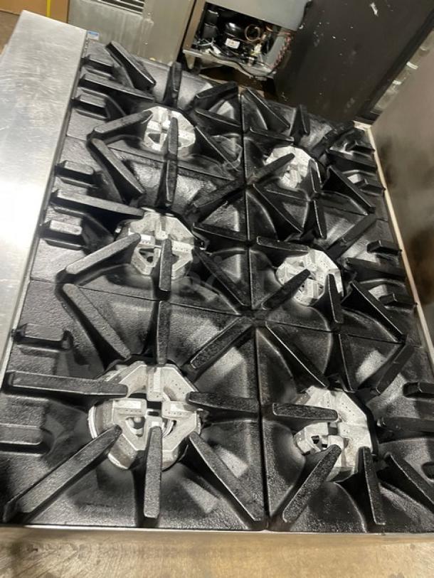 U.S. Range commercial stainless steel 6-burner gas range with backsplash, dry cabinet-style storage base, on casters.