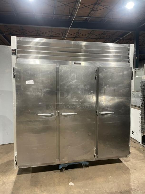 Traulsen G31010 commercial stainless steel triple door reach-in freezer with poly coated wired rack, on casters.