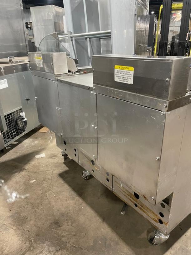 Pitco Frialator 2-bay fryer system, stainless steel, with center cabinet, backsplash, basket hanger, and casters. Visible caution labels.